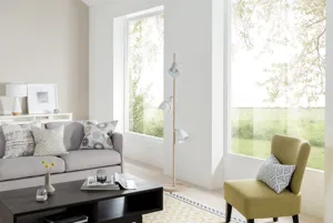 Living room with cream walls, chartreuse chair, low coffee table and oatmeal sofa with two large picture windows, undressed.