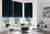 Modern dining room with bay window dressed in three navy blue velvet Roman blinds, oval glass table, metallic gold chairs with blue upholstery, metallic gold side table with blue glassware.