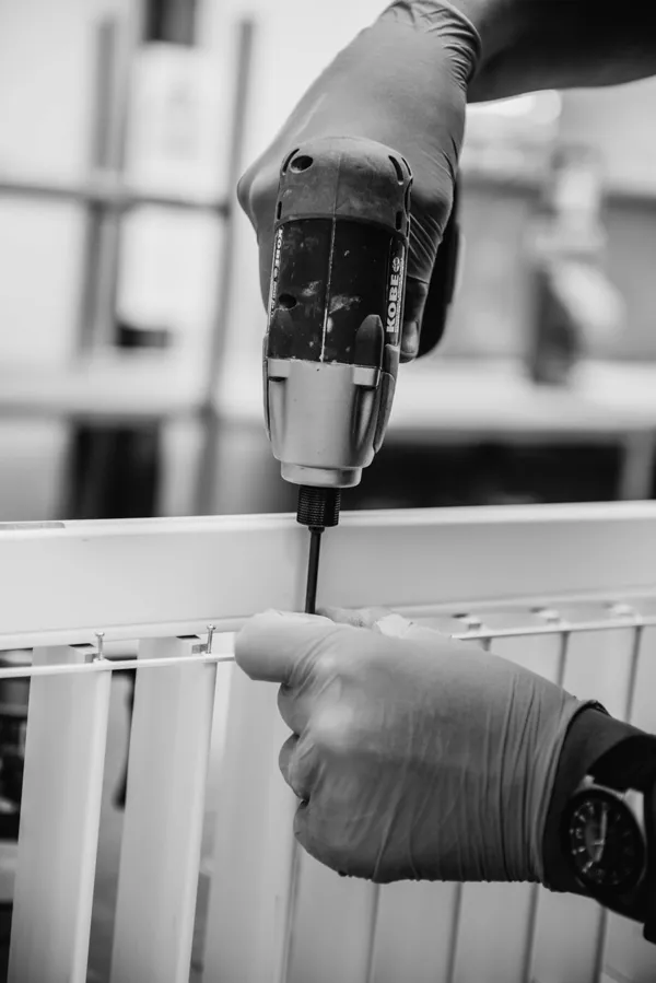 close up of employee using a drill to help make a shutter in a factory