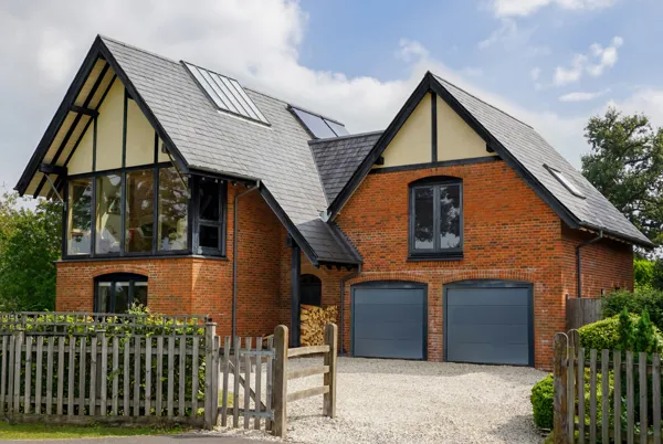 Large house with attached garage and second storey block with two grey sectional garage doors.