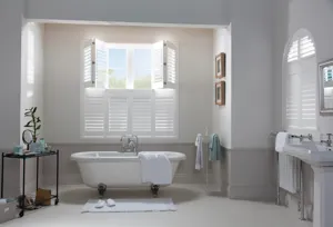 White coloured tier on tier shutters fitted to a window in a bathroom that is decorated in grey and white 