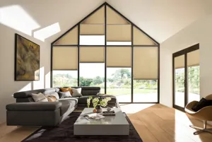 Gable end windows and doors in living room with buttermilk walls, brown sofa, grey low table, wood floor, French doors on right hand wall, all windows and doors dressed in pale caramel Duette blinds at varying heights.