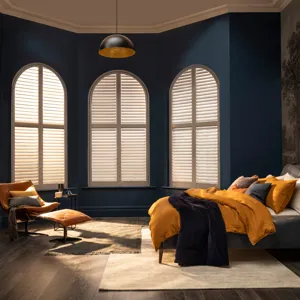 arched shutters in dark navy bedroom with orange furnishings