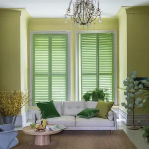 green tier on tier shutters fitted to tall windows above a sofa in a living room