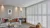 White wooden shutters fitted to a wide window in a living room with a sofa, chair and coffee table
