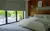 Bedroom interior with partially raised sage green Roman blinds looking out into garden over the patio.