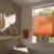 Bathroom with picture window in white wall, dressed in a cadmium orange blind in the middle of the window, side wall and floor tiled in metro stile in shades of brown, grey and copper, white bathtub in centre, pale wood shelf with white sink, cadmium orange towel on rail by window.