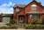 Two storey dark brick house with separate garage with sage green garage door matching front door.