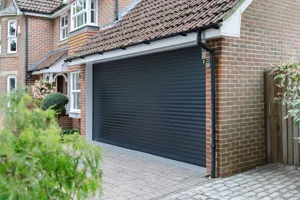 Beige brick townhouse style property with integral garage and garage door in dark grey matching the front door and window frames.