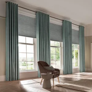teal coloured eyelet curtains fitted across three windowsand matched with blinds in a room with a an armchair and side table