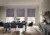 Dining room with three tall windows dressed in mid blue duette blinds, dining chairs in blue, blue sideboard on right.