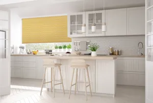 Bifold doors reveal kitchen in white tongue and groove with matching island and high wood stools and wide window dressed in mustard yellow roller blind with wave pattern.
