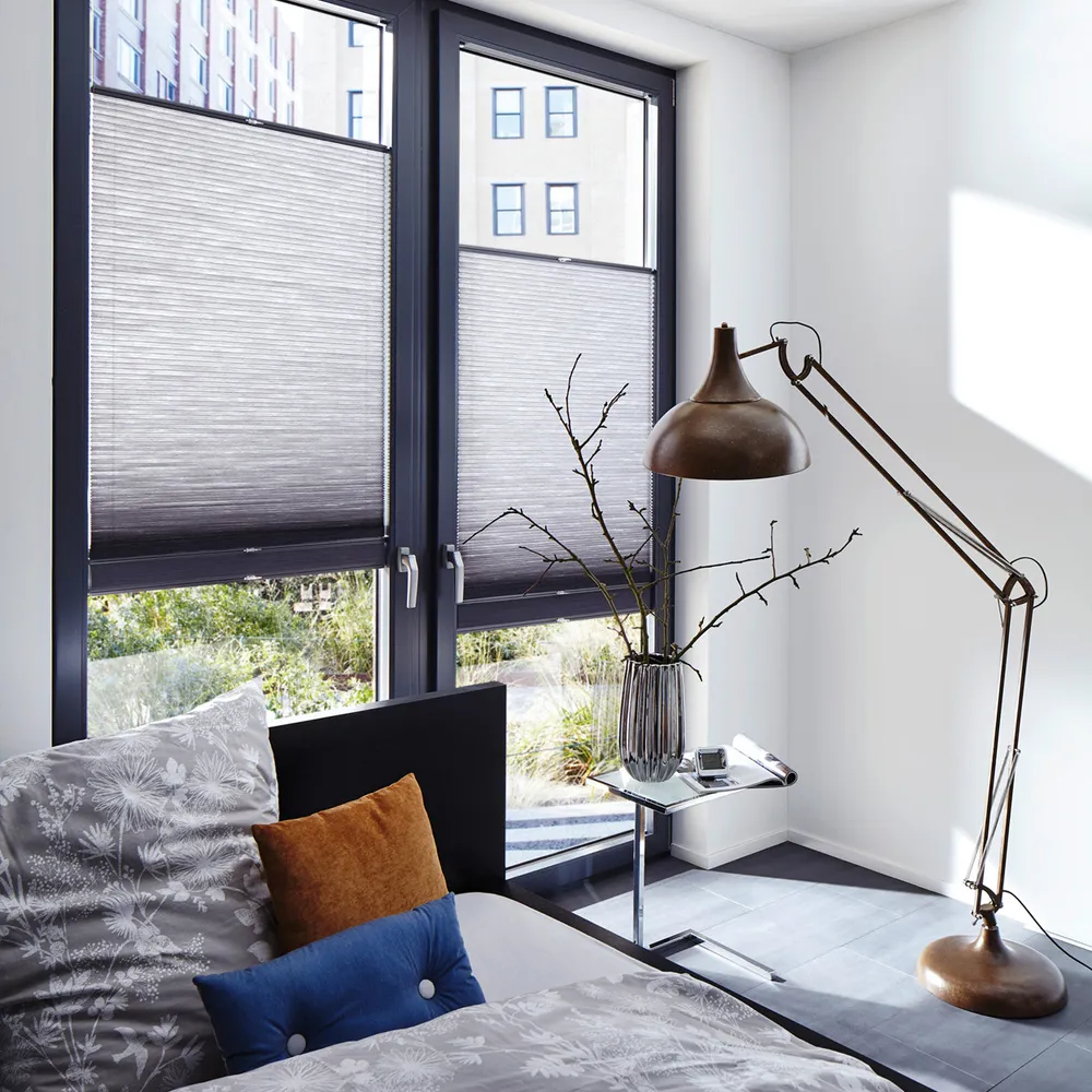 Two grey Duette blinds covering middle sections of doors, grey anglepoise lamp and vase with twigs. 