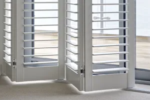 Close up of white tracked shutters, partially folded back.