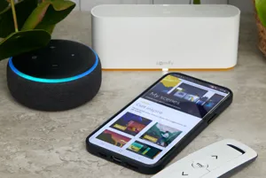 Marble surface with white hub, Amazon Echo Dot device, smartphone and slimline white remote control.