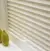 Pale peach marble effect pleated blind lowered, with conical chartreuse-green vase on sill.