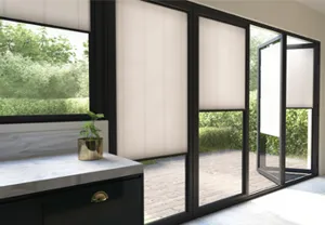 Tall windows and bi-fold doors in dark frames, dressed with soft white Micro Hive blinds, the bi-fold door is partially folded open.