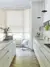 Kitchen in white with cream units and pale parquet floor, marble worktops and bat window dressed in roller blind in cream with wheatsheaf pattern.