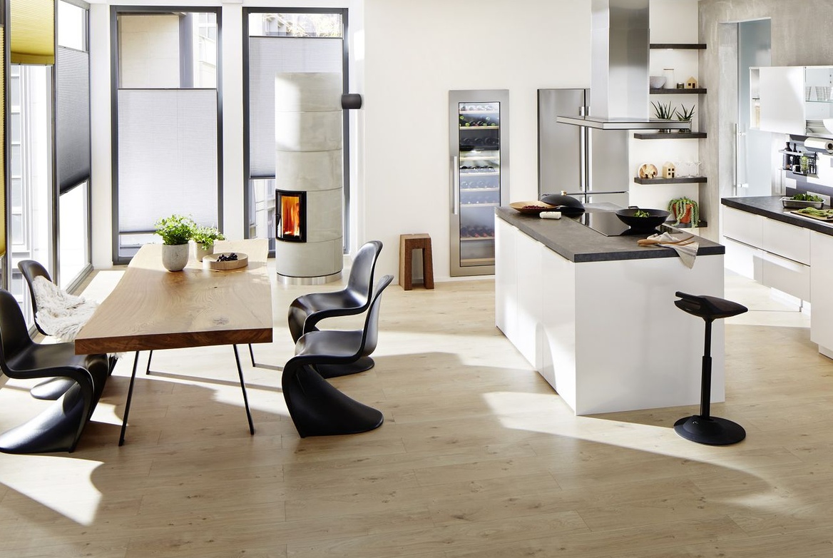 Open plan kitchen dinner in white with white units, dark worktops and appliances in silver.