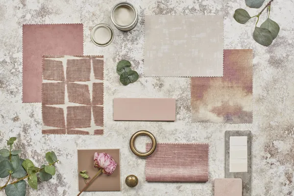 Moodboard of spring vibes in shades of dusky and deep pinks, with fabric swatches in plains and patterns, brass and steel curtain rings and dried roses and stems.