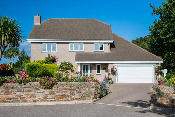 60s-style property in floral setting with dormer integral garage with white sectional garage door and matching front door.