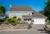 60s-style property in floral setting with dormer integral garage with white sectional garage door and matching front door.