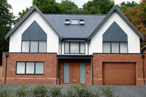 Large contemporary two-tone house with apex windows, integral garage with light brown garage door matching front door.
