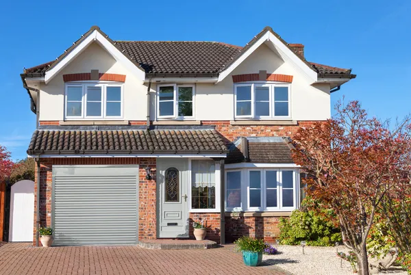 Modern two tone white and brick house with integral garage with olive green roller garage door matching the front door.