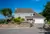 60s-style property in floral setting with dormer integral garage with white sectional garage door and matching front door.