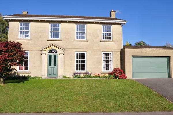 Georgian-style property with attached garage with sectional garage door in  sage green matching the front door, white crittal windows.