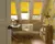 Yellow coloured blinds fitted to skylight windows in a study with a wooden desk, white tub chair and wooden flooring