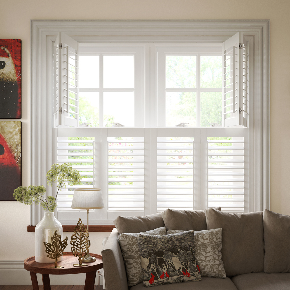 Living room with cream walls, abstract art on wall, brown sofa in front of a wide window dressed in white tier on tier shutters, top section open, bottom closed with louvres open.