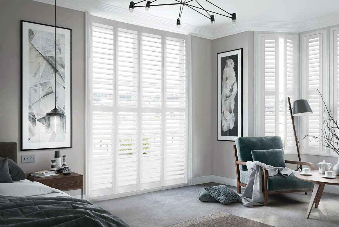 Dove white shutters fitted to tall windows in a light & dark grey decorated bedroom