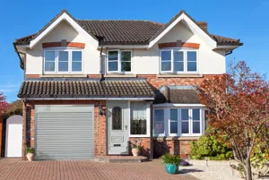 Modern two tone white and brick house with integral garage with olive green roller garage door matching the front door.