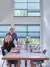 Matt and Lisa Tebbutt in dining room with double height windows dressed in mid blue duette blinds, wooden dining table and blue chairs.