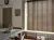 Dining room in soft white with large window dressed in mid brown wooden venetian blinds, lowered, slats tilted, grey table  and door, white bench in window recess with white ceramic vase underneath.