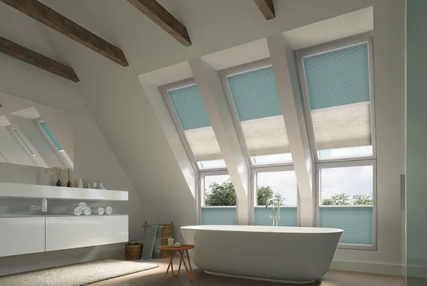 Bathroom with three windows in eaves, beamed ceiling with white sinks units, white bath under windows dressed in twinshade duette blinds in blue and pale grey