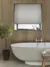 Bathroom with deep recessed window dressed in pale grey-beige roller blind, walls with wood panelling, roll top bath with central mixer taps, small bay tree in pot to left.