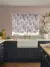 Kitchen with a window dressed with a roller blind in a pink, grey and beige waterfall pattern, dark blue cabinets, dusky pink walls and behind a butlers sink with antique brass mixer taps.