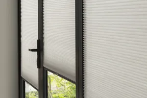 Close up of a pale grey honeycomb blind in a door and two windows, all in one complete unit.