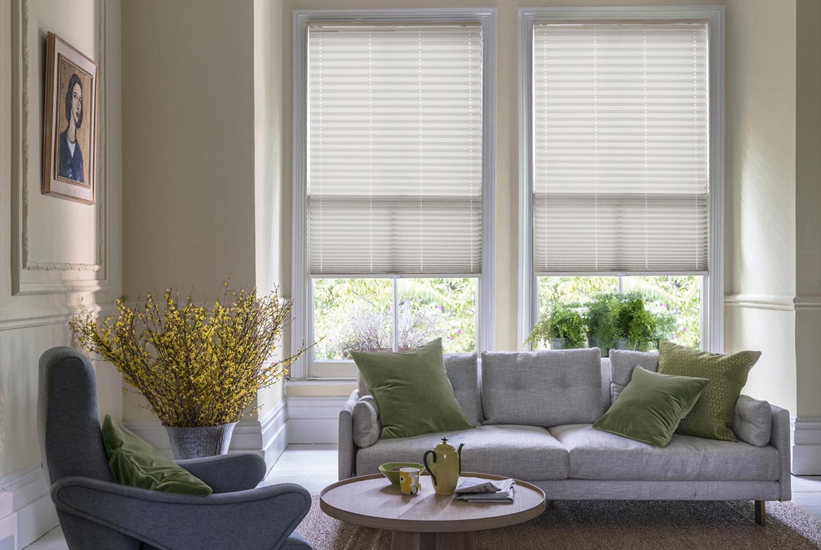 natural Pleated blinds have been fitted to multiple windows in a luxuriously styled kitchen in marble and white. Solartex Crush Champagne Crush has a plain style that complements the room.