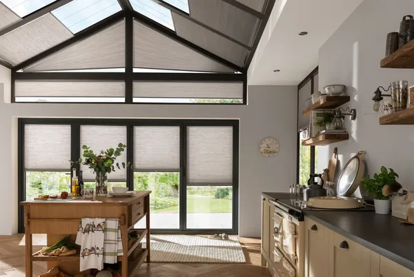Kitchen with wooden island in front of a gable end window dressed in ochre blinds at varying levels.