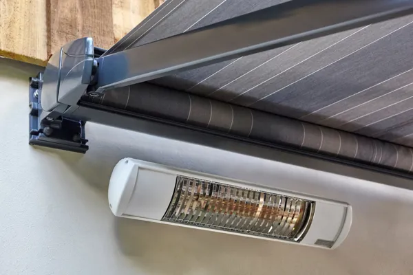 Close up of a small wall heater mounted underneath a grey striped awning.