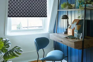 Home office with wood panel walls in cobalt blue and sky blue, tall wood desk and shelving, window dressed in dark blue blind with white honeycomb-type pattern.