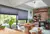 Dining area with door and window combination dressed in blue-grey duette blinds partially lowered, rustic wooden table and benches underneath a roof lantern window.