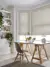 Home office with pale wood floor and large abstract pattern rug, trestle table desk with small angle poise lamp over laptop in front of bay windows dressed in roller blinds with a pale brown swirling pattern.