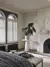 white shutters fitted to an arch shaped window in a bedroom decorated in white with a rug and wooden flooring