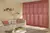 Living room in cream with brown rug, pale beige sofa with terracotta cushions in plain and patterned fabric and floor to ceiling shutters in terracotta, louvres open.