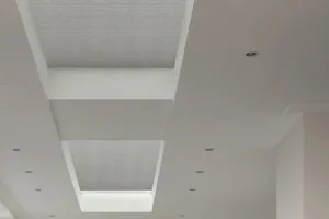 Two roof lantern windows in a white ceiling dressed in pale grey duette blinds, extended.